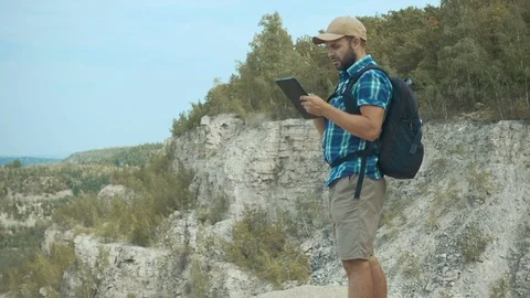 Tourist man He is standing in the mountains, and using tablet . men with bac Stock Footage