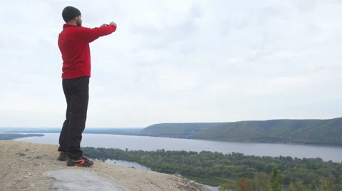 Tourist man He is stands in the mountains, and using smartphone photographing Stock Footage