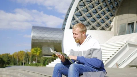 Tourist with a map sitting on the steps of a modern building Stock Footage 103091219