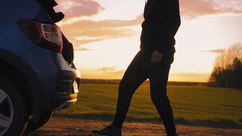 The tourist opens the trunk of the car in the middle of the field at sunset Stock Footage 95329622