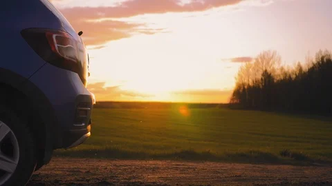 The tourist opens the trunk of the car in the middle of the field at sunset Stock Footage 99924562