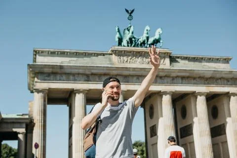 A tourist or a guy with a backpack is talking on a mobile phone and is greeting Stock Photos