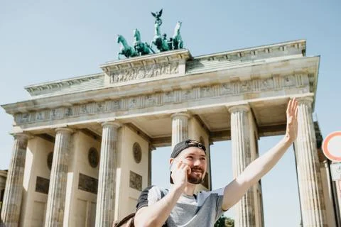 A tourist or a guy with a backpack is talking on a mobile phone and is greeting Stock Photos