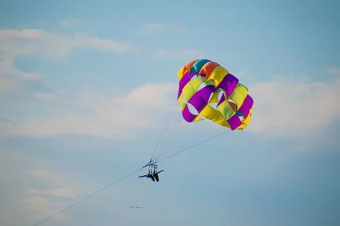 Tourist parasailing with the help of security in the cloudy sky on a sunny da Foto stock