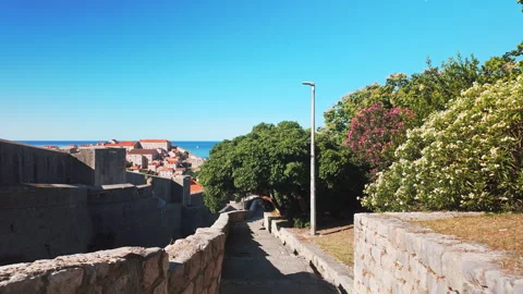 Tourist perspective walking down stone steps toward historic Dubrovnik, Croatia Stock Footage 343884426