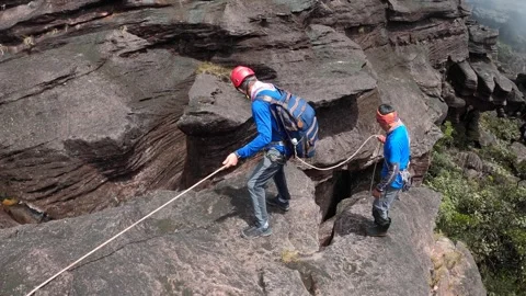 Tourist preparing climb down a rope from rock under guidance of instructor Stock-Footage 251806024