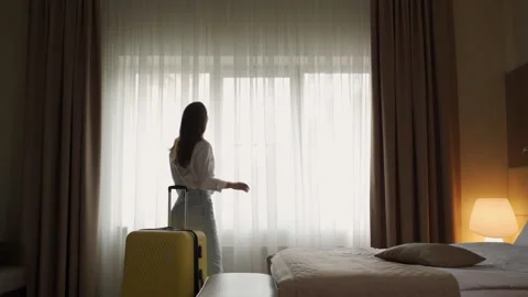 Tourist pulls back white curtains to enjoy view from window Stockbeeldmateriaal 208423477