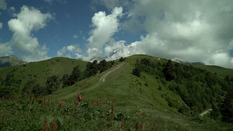 Tourist in a red jacket rises to snow capped mountains. Very beautiful nature Stock Footage 115963747