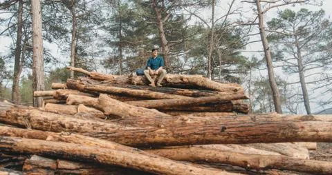 Tourist resting on stack of woods Stock Photos