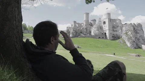 A tourist resting under a tree and admiring the view of the Ogrodzieniec Stock Footage 131225016
