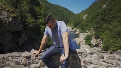 Tourist sitting on the side railings of the Devil's Bridge, located right Stock Footage 259152007