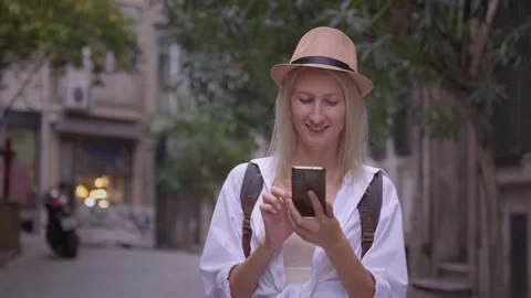 Tourist with smartphone and backpack on shoulders looking at smartphone city 動画素材 252901385