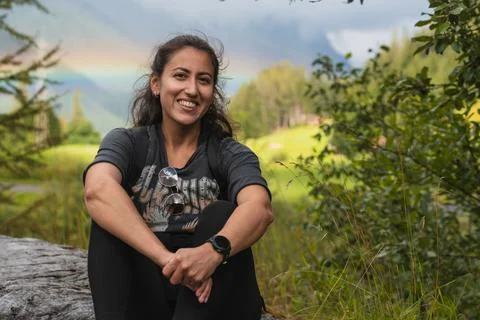 Tourist smiling with rainbow in the background while hiking in the alps Stock Photos