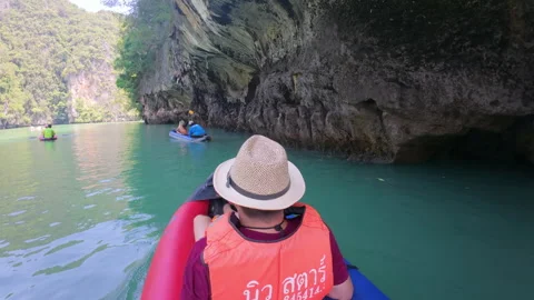 Tourist in straw hat kayaking through green water and limestone cliffs Stock Footage 311269738