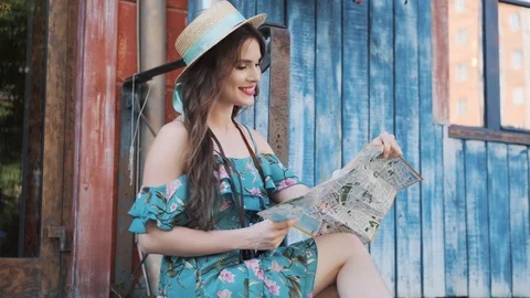 Tourist is studying the map while sitting on the steps. young woman in a hat Stock Footage 118976472