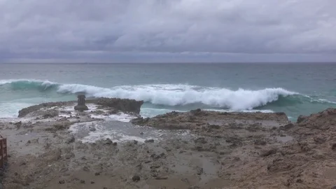 A tourist takes a photo of surf pounding the shoreline Stock Footage
