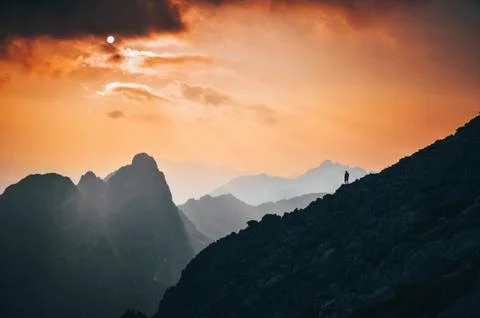 Tourist on the top of the hill under cloudy sky in mountains - nature scenery Stock Photos