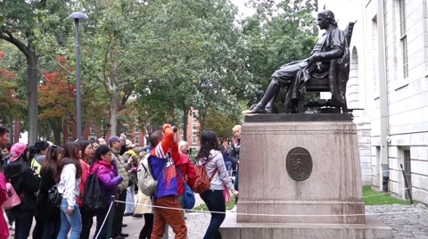 A tourist touching John Harvard statue for good luck Stock Footage 56348231