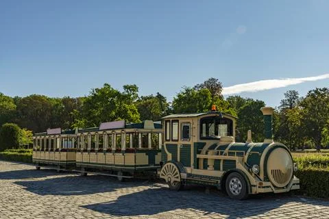 Tourist Train Parked on Cobblestone Path in Sunny Park Foto stock