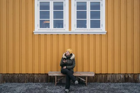 Tourist using mobile phone while relaxing on bench in lofoten islands Stock Photos