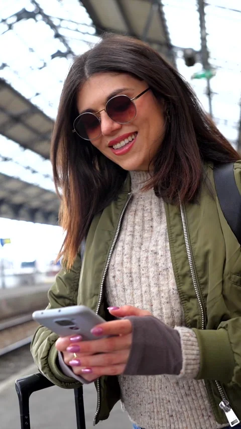 Tourist using smartphone and smiling at train station Stock Footage 311809573