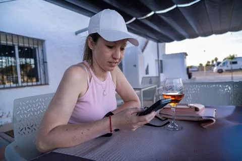 Tourist using smartphone at restaurant table with drink during summer vacatio Stock Photos