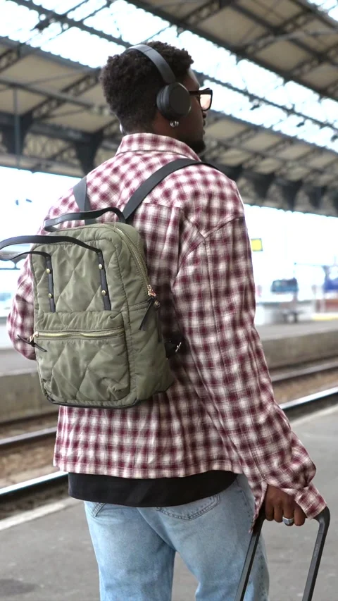 Tourist walking in train station pulling suitcase wearing backpack Stock Footage 311809564