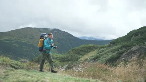 A tourist walks with a backpack in the mountains. A guy on a hike Stock Footage 217395207