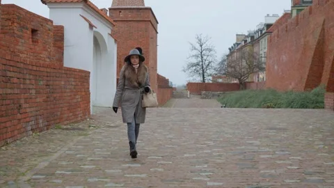A tourist walks on a cobblestone path exploring the Warsaw Barbican. Stock Footage 311708567