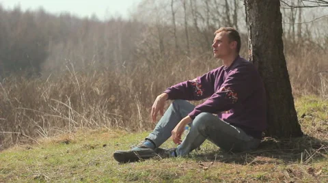 Tourist,guy tired,boy sitting under a tree,Guy examines all around Stock-Footage 48631934