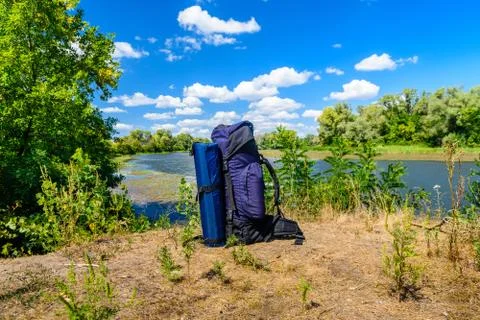 Touristic backpack on a bank of river Stock Photos