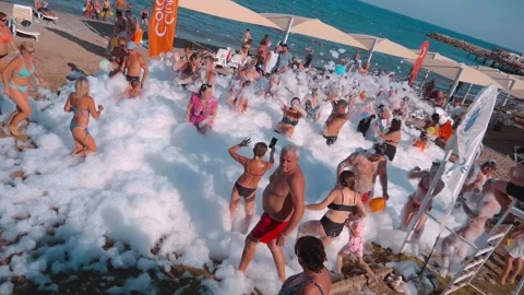 Tourists are having a great time dancing to cheerful music in the foam Stock Footage 323920032