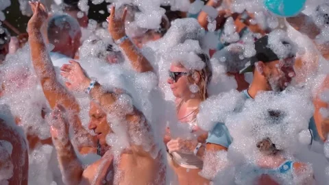 Tourists are having a great time dancing to cheerful music in the foam Stock Footage 323920206