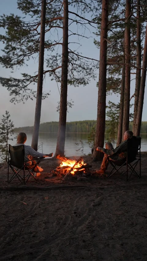Tourists are warming themselves by the campfire with a view of the lake. A Stockbeeldmateriaal 307004685