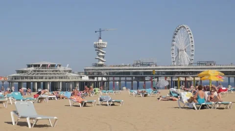 Tourists on beach chair with pier and ferris wheel,Scheveningen,Netherlands Stock Footage