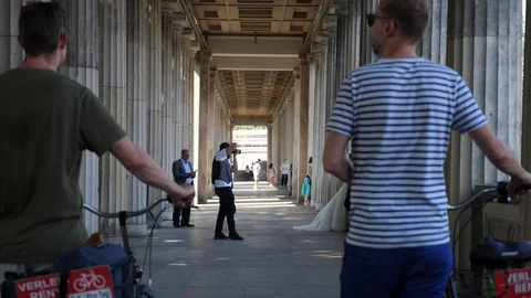 Tourists with bikes walking through old column pathway near National Gallery 스톡 동영상 116252098