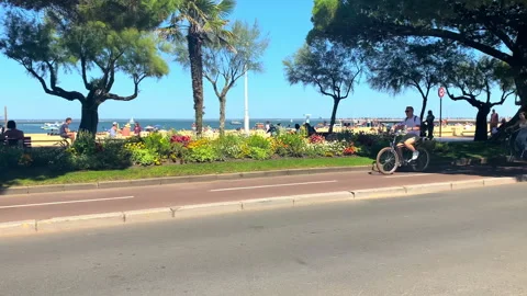 Tourists biking on a cycle path of the seafront of Arcachon on a summer day Stock Footage 172591306