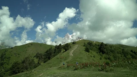 Tourists in a blue jacket rises to snow capped mountain amazing beautiful nature Stock Footage 115963682