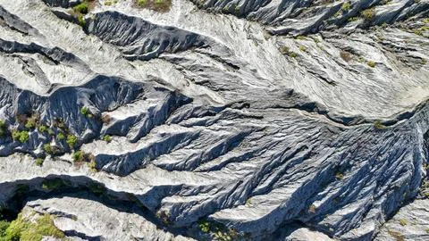 Tourists dot the edge of Bromo epic ash valley, framed by steep gray cliffs and Stock Photos