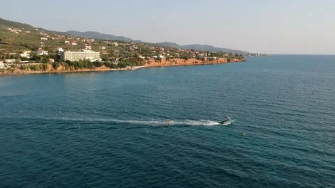 Tourists enjoy inflatable towable rides at Almyros beach in Kato Verga, Kalam Stock Footage 200046645