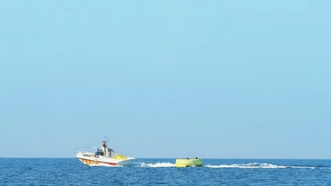 Tourists Enjoy Skiing on Inflatable Behind Speed Boat Stockbeeldmateriaal 117950448