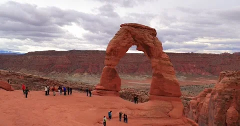 Tourists explore the landscape near Delicate Arch in a desert canyon. Vídeos de archivo 334013410