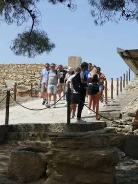 Tourists exploring ancient stone pathway near ruins of Knossos Palace, Crete Stock Photos