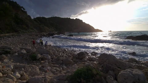 Tourists exploring the coastline and playing with strong waves. Video stock 244842129