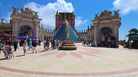Tourists exploring Eclipse Square with glass pyramid at Sun World Ba Na Hills Stock Footage 332457980