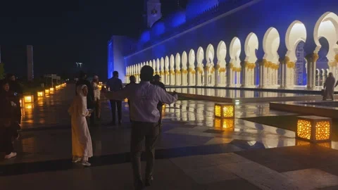 Tourists exploring exterior grounds at Sheikh Zayed Grand Mosque under vibrant Stock Footage 339763704
