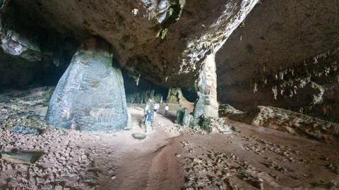 Tourists exploring large limestone cave with stalactites Stock Photos