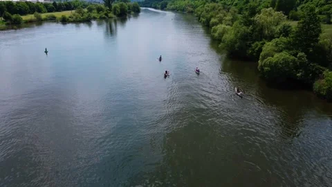 Tourists float on the river kayaking near the green field Stock Footage 155413537