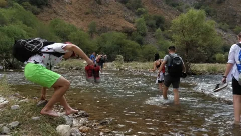 Tourists ford a mountain river Stock Footage 160070855