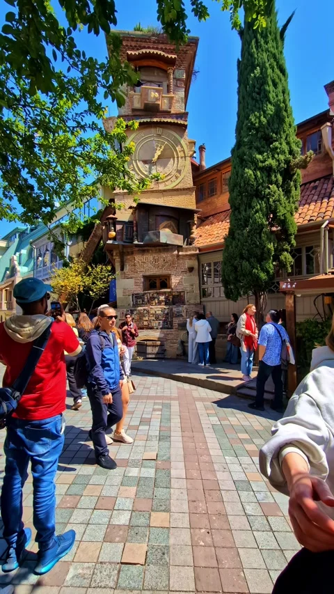 Tourists gather at the iconic Clock Tower in Old Tbilisi on a bright sunny Stock Footage 340073482